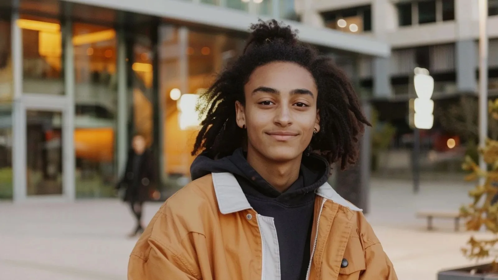 Portret van een MBO-student bij de ingang van de locatie. Voltijd, dagelijks contact met cohort en coach